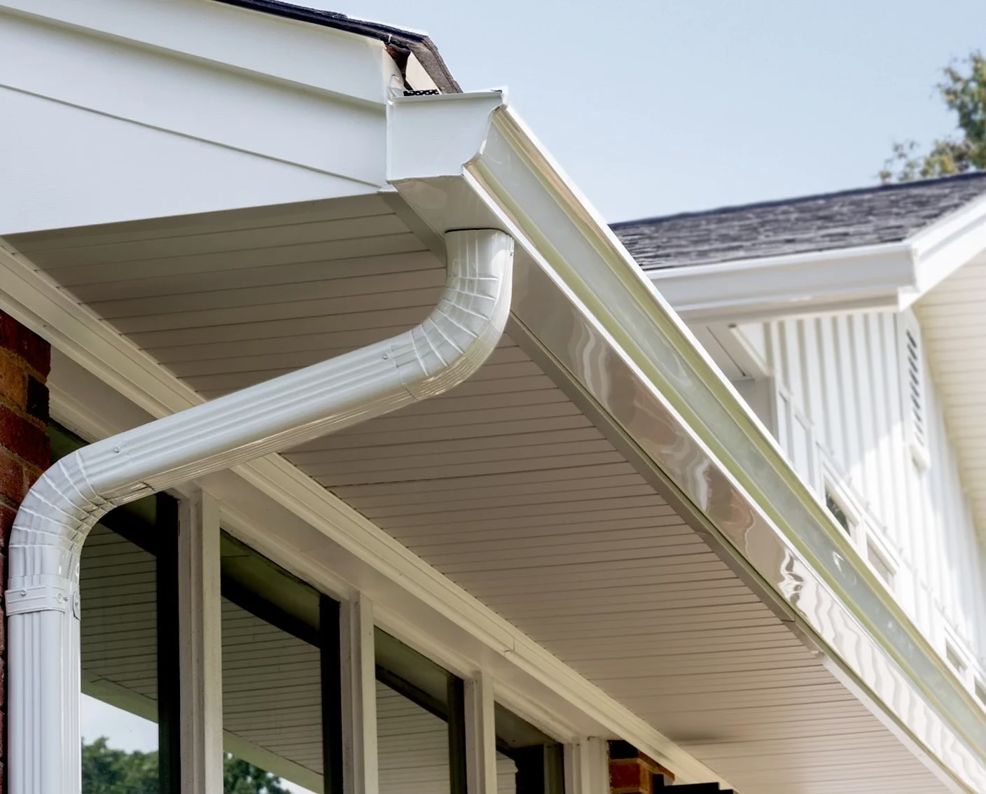 Newly installed white gutters and downspout on a residential house